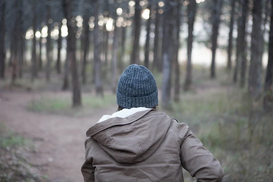 Eine Person, die eine Mütze trägt und mitten im Wald rennt