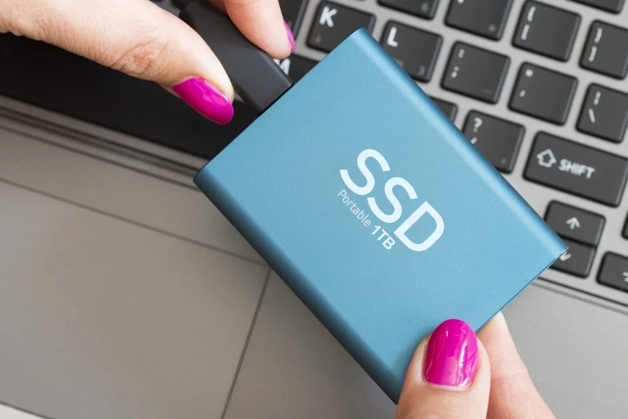 senhora segurando um SSD portátil azul de 1 TB