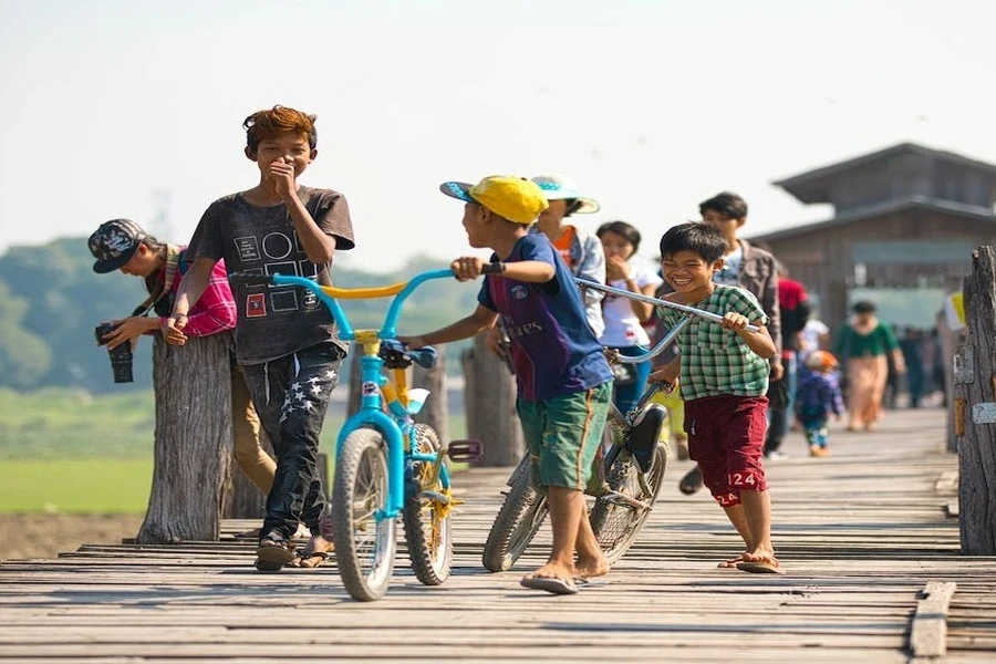 Algumas crianças andando enquanto empurram suas bicicletas