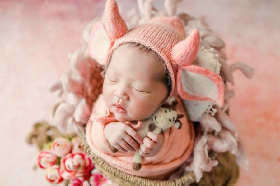 Seorang bayi baru lahir terbungkus bedong dan topi berwarna oranye