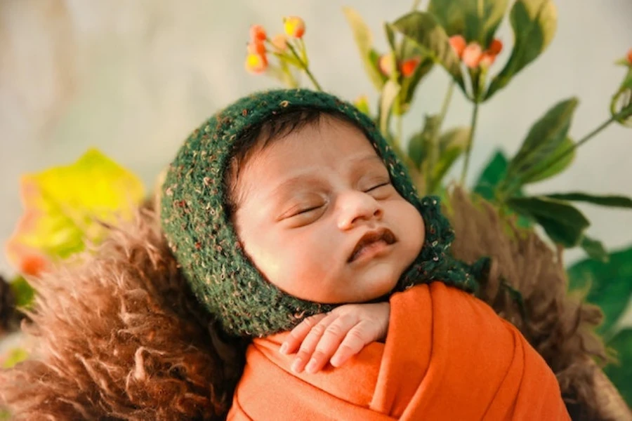 Seorang bayi baru lahir mengenakan bedong dan topi rajutan