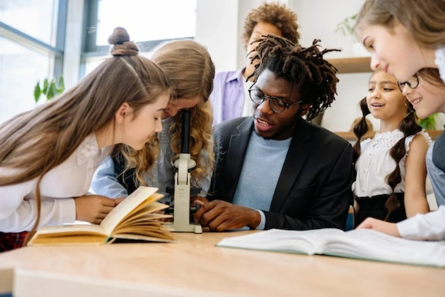 Um professor ensinando aos alunos como usar um microscópio