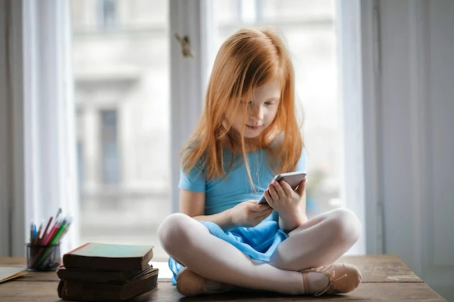 una niña sosteniendo un teléfono inteligente