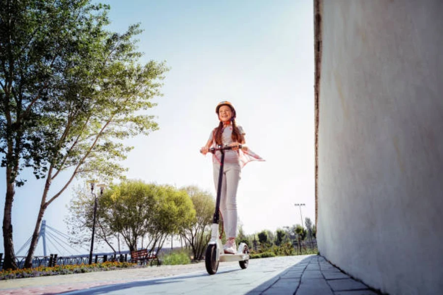 Girl riding an electric scooter with a matching helmet