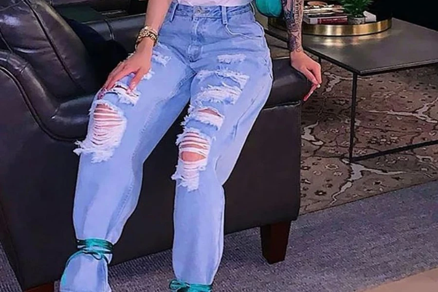 Señora sentada en un sofá con jeans desgastados