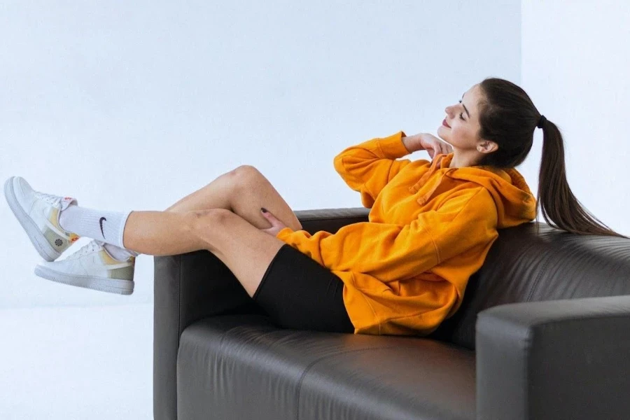 Dame trägt eine Biker-Shorts und ein orangefarbenes Sweatshirt