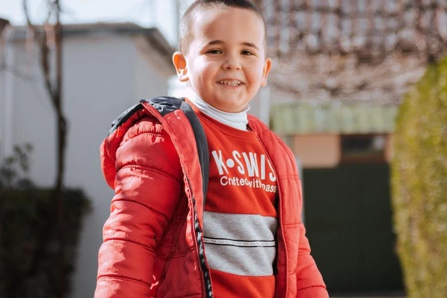 Niño sonriente vistiendo una chaqueta acolchada roja