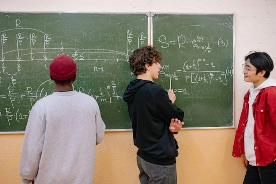 Tres estudiantes parados detrás de un tablero