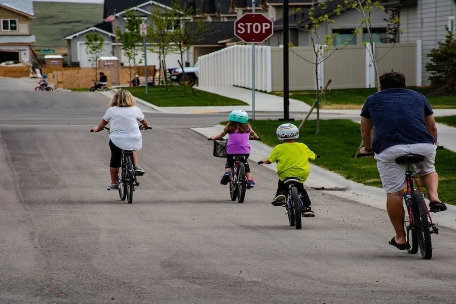 Duas crianças e seus pais andando de bicicleta numa rua