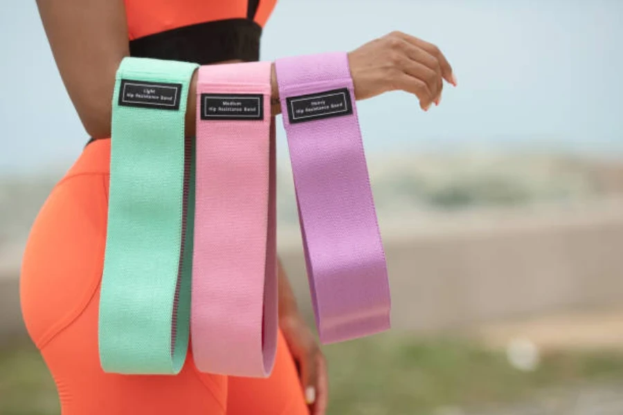 Woman holding three colorful mini bands for workout