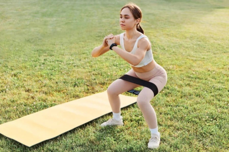 Donna che utilizza una fascia di resistenza nera per tutto il corpo per gli squat