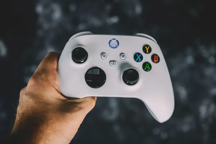 Una mano che tiene un controller Xbox bianco