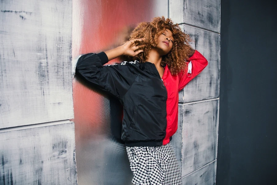 Señora posando con una chaqueta bomber negra y roja