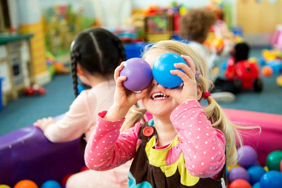 Bambina che gioca in un piccolo pozzo di palline al coperto