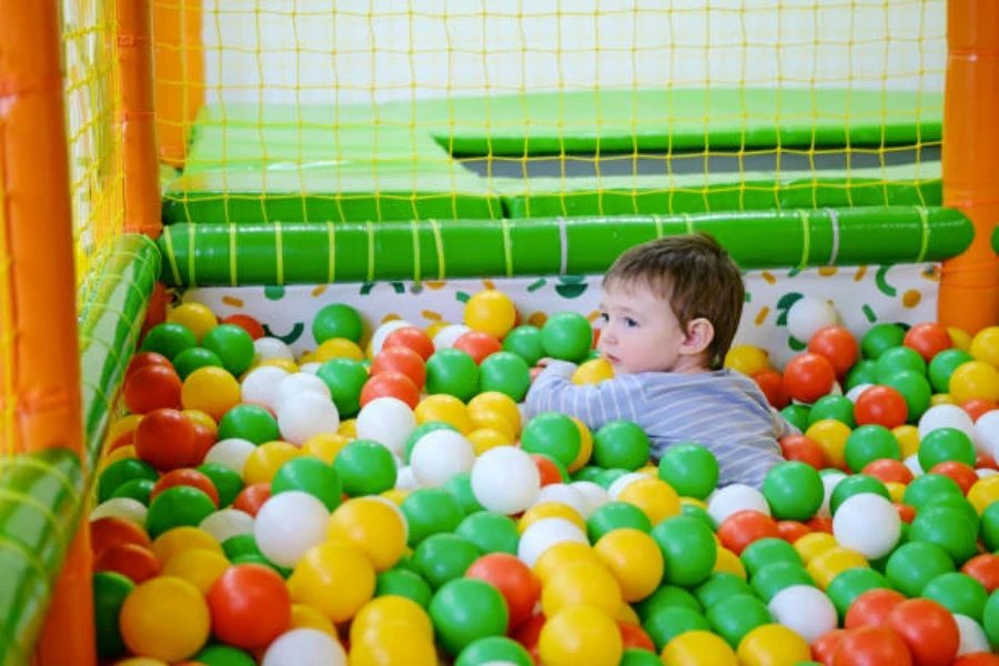 Bambino maschio che gioca in una vasca di palline morbide al chiuso