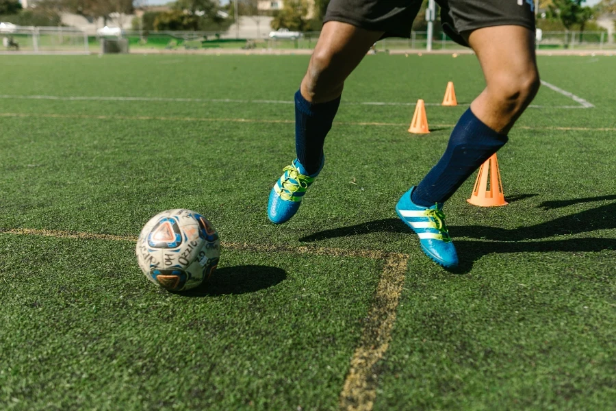 Mann in blauen Stiefeln trainiert mit einem Ball