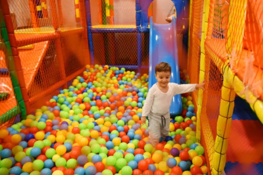 Niño pequeño jugando dentro de la piscina de bolas en el patio interior