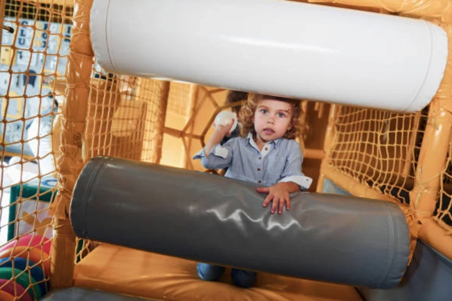 Small girl crawling through ball pit obstacle course