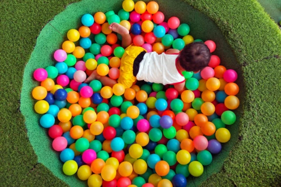 Balita bermain di dalam lubang bola bulat kecil dengan bola berwarna-warni