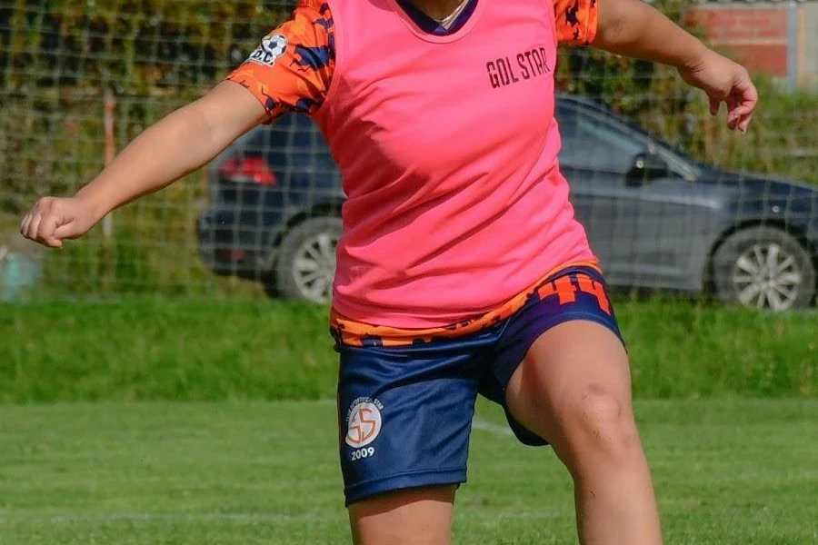 Frau übt in einem rosafarbenen Fußball-Pinnie