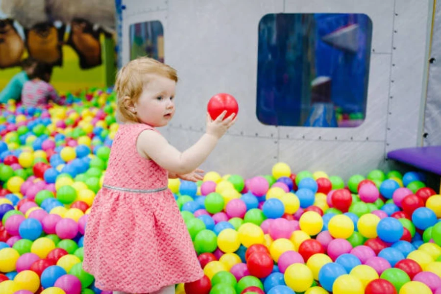 屋内の宇宙をテーマにしたボールピットで遊ぶ若い女の子