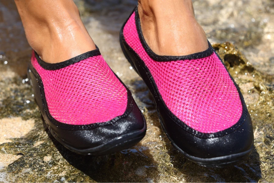 Piedi di donna in scarpe da acqua rosa e nere