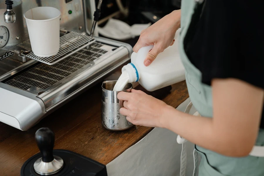 Barista versant du lait d'un pichet