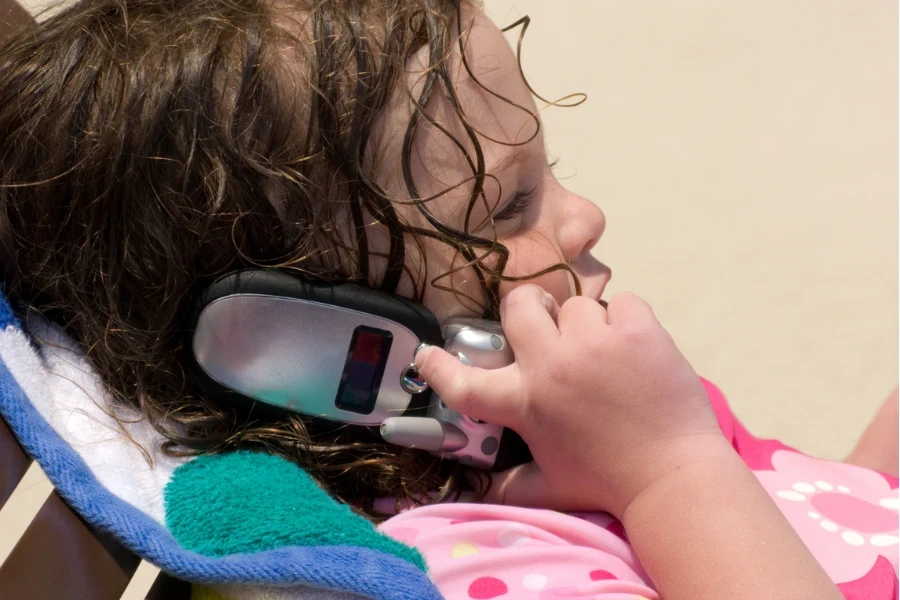 Niño tomando con teléfono plegable en la mano