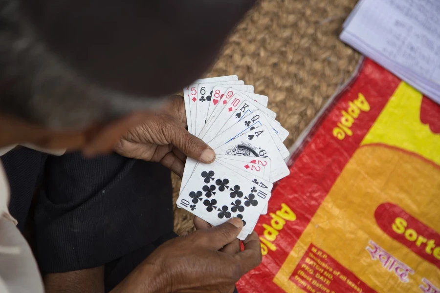 Homem segurando uma seleção de cartas de baralho de plástico com as duas mãos