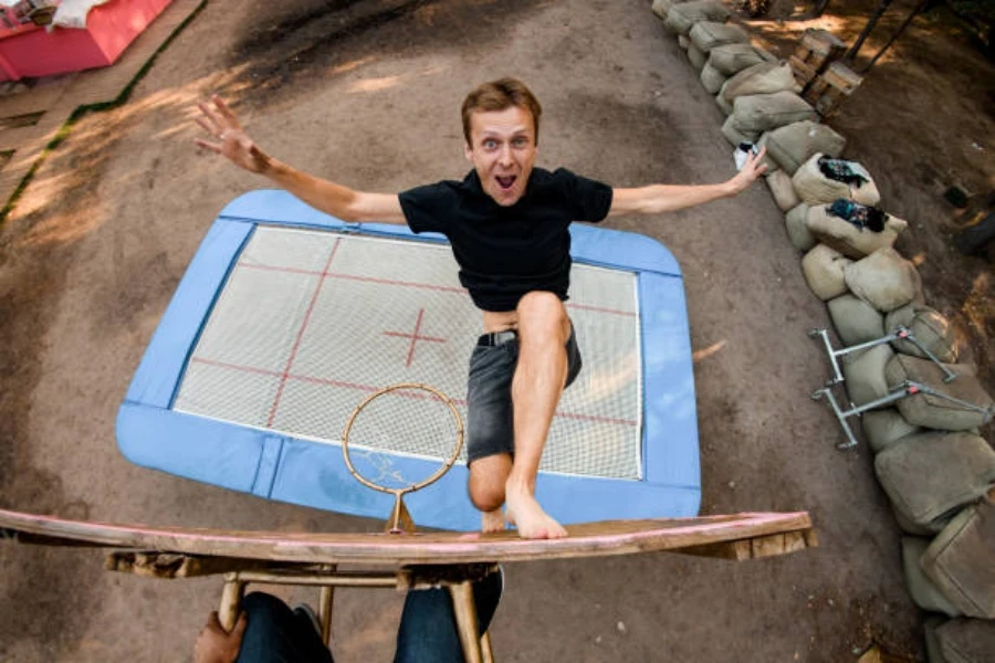 Mann springt vom Trampolin auf die Höhe eines Basketballkorbs