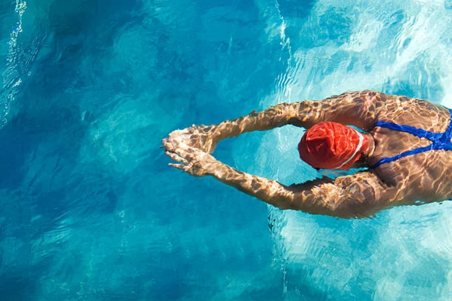 Person swimming in pool wearing a red swimming cap