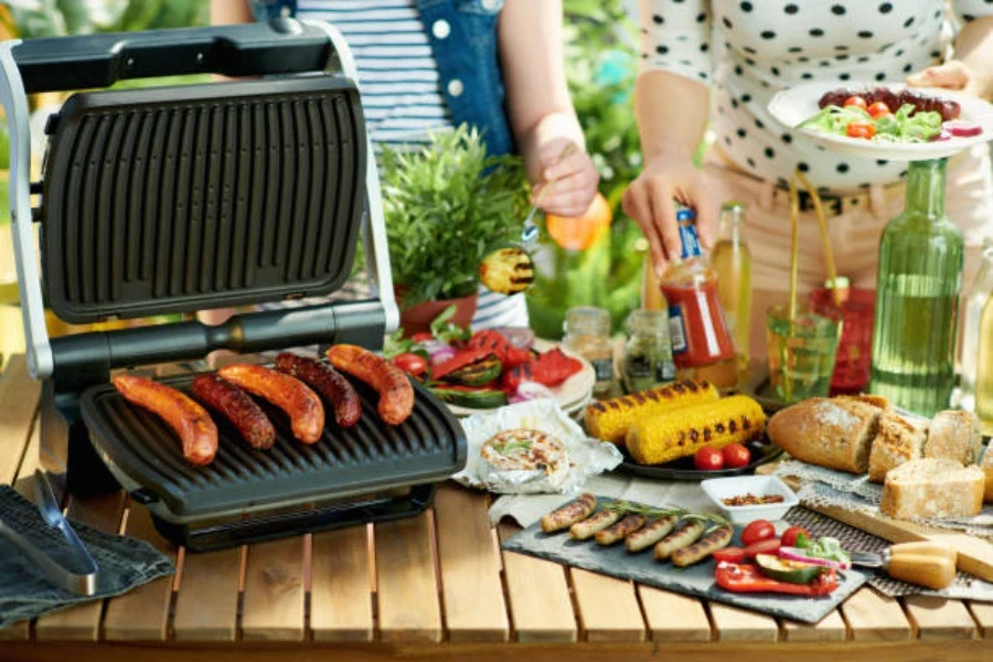 salsicce alla griglia sulla griglia elettrica durante il picnic all'aperto