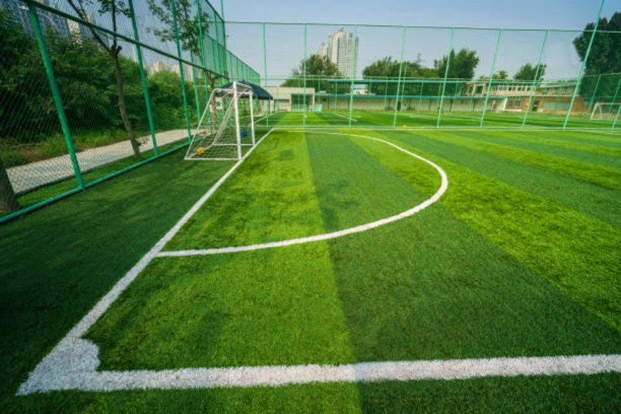 Pequeno campo de futebol fechado com grama artificial instalada ao ar livre