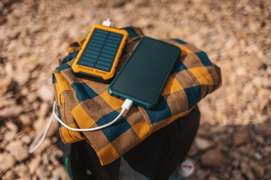 Smartphone branché sur une banque de batteries alimentées à l'énergie solaire posée sur un sac à dos