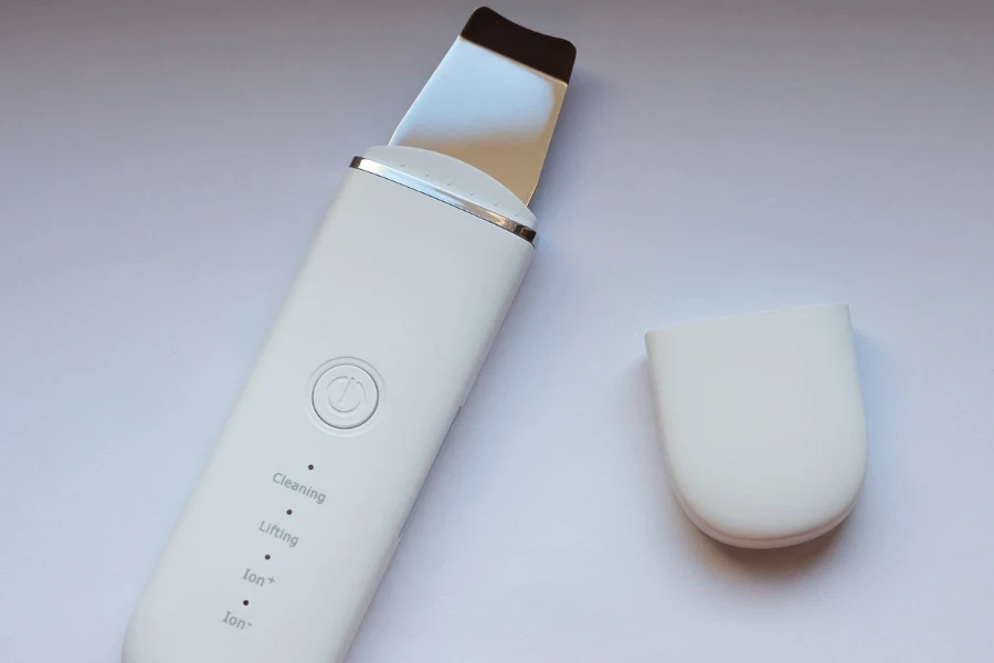 White wireless ultrasonic skin scrubber on a gray background