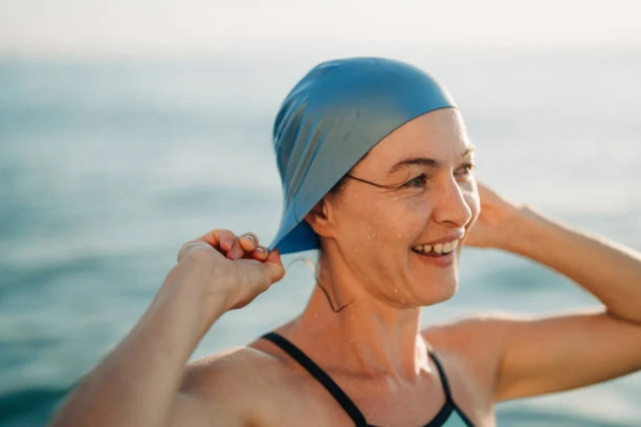 Frau setzt im Meer eine Silikon-Badekappe auf