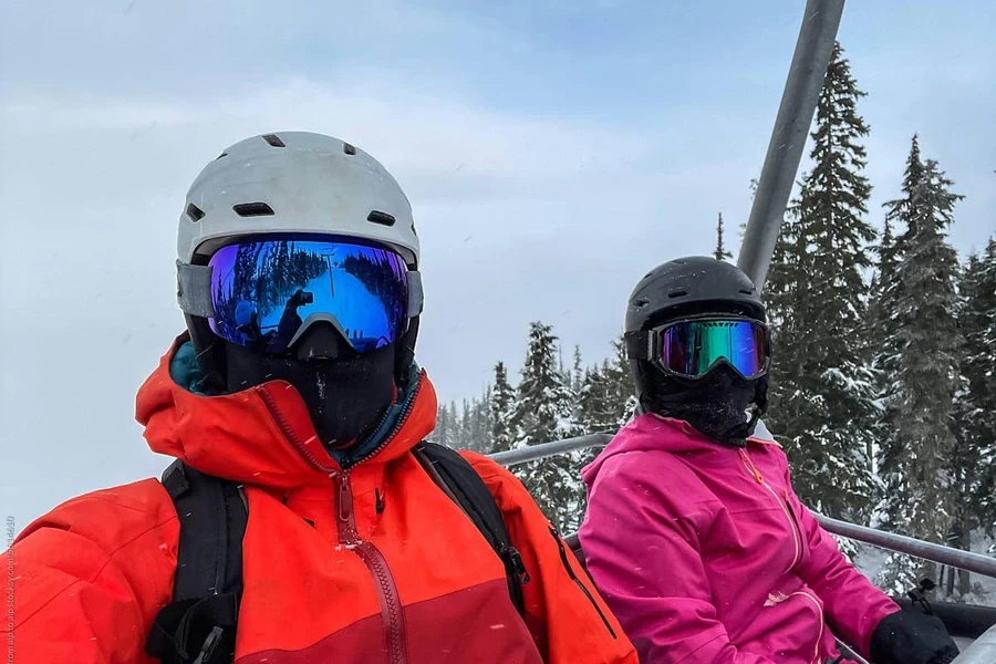 un couple portant des masques de ski monte sur un téléphérique