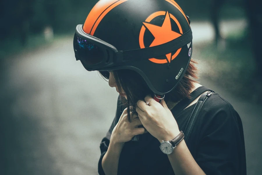 Senhora usando um capacete de equitação preto e laranja