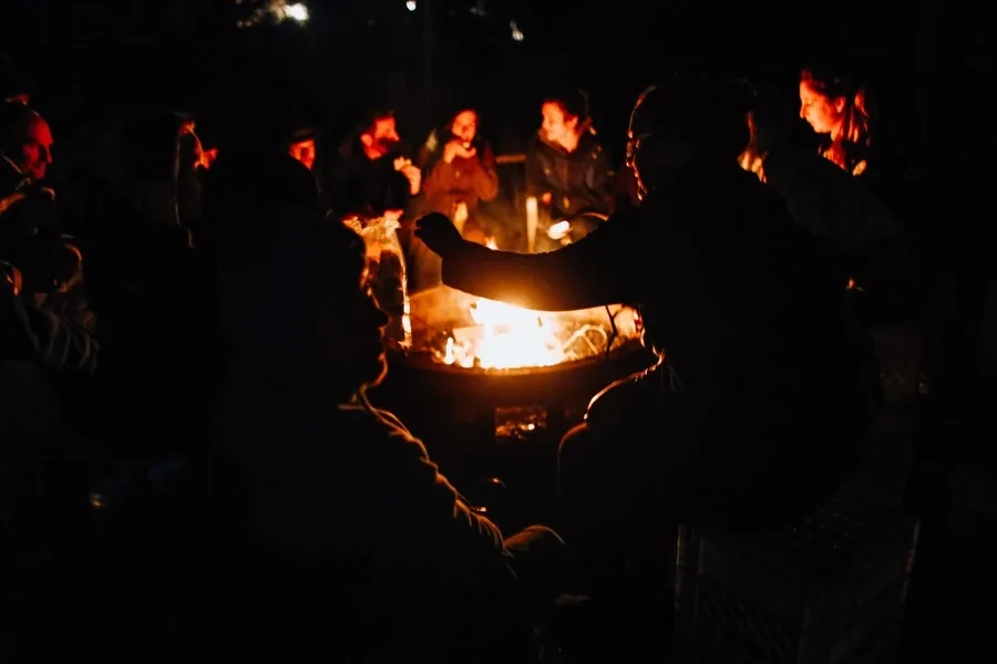 Menschen rund um eine Feuerstelle im Freien