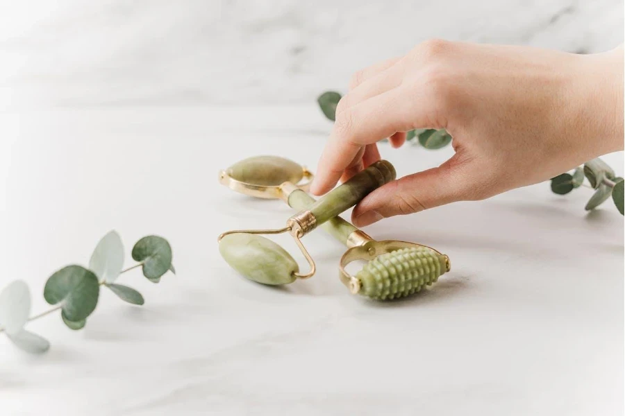 Mão feminina segurando rolo derma verde oliva