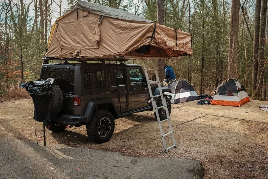 Ormanda 4x4'ün üstüne kahverengi çatı çadırı kurulumu