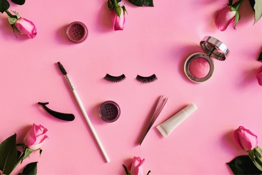 Eyelash glue and other beauty tools on a pink table