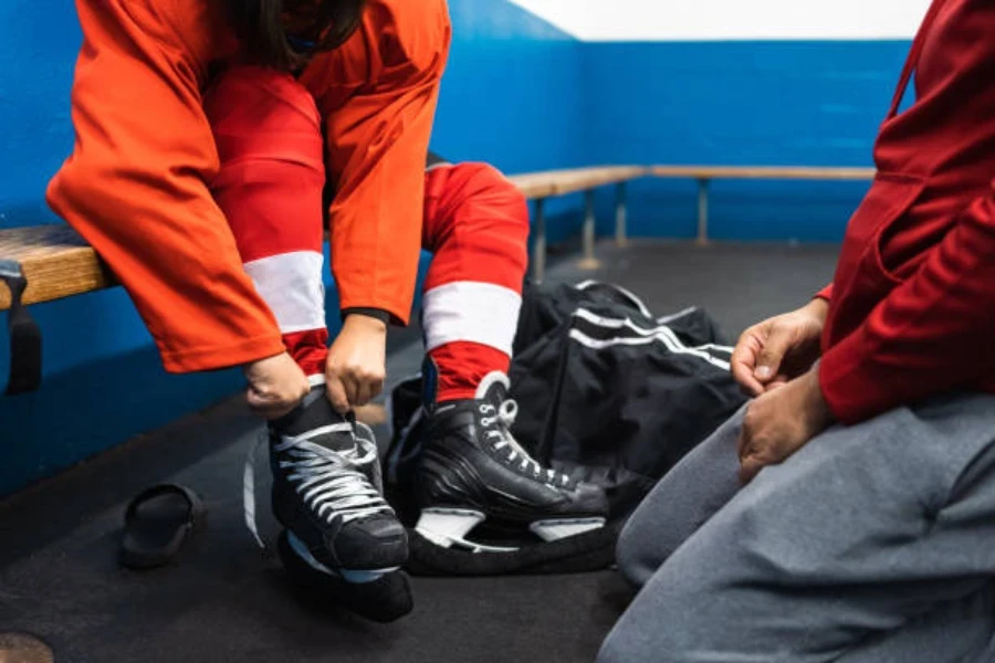 Jogador de hóquei no gelo amarra patins de gelo para treinar