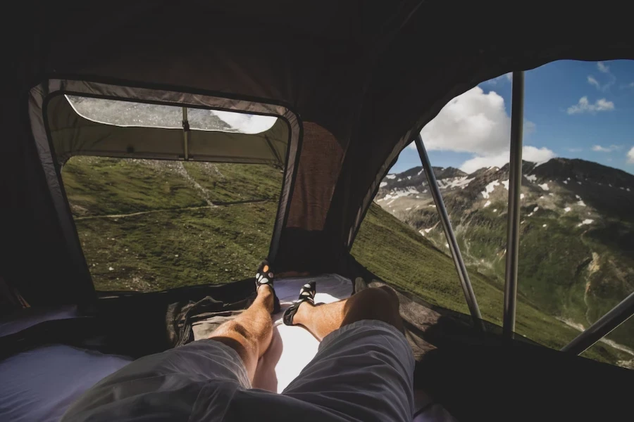 Homme couché dans une tente sur le toit avec vue sur la montagne