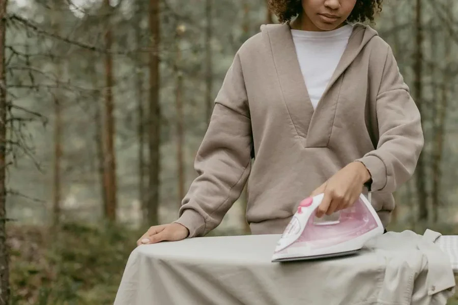 Una ragazza stira una camicia su un asse da stiro