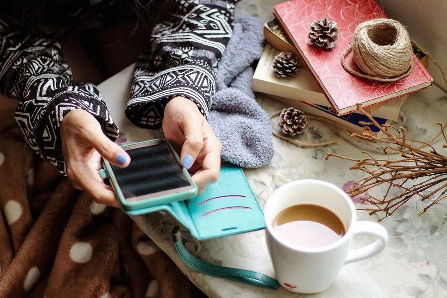 Una ragazza che usa lo smartphone mentre beve il tè