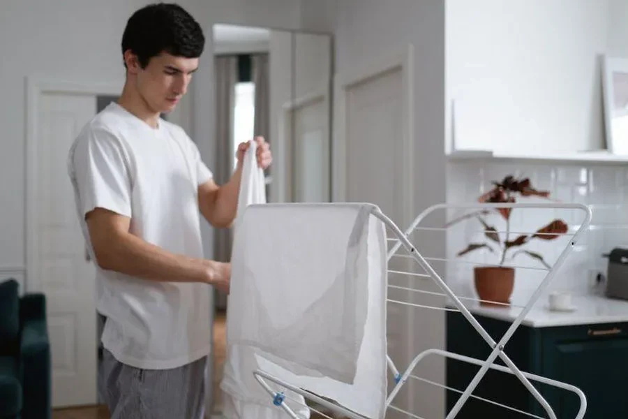 Ein Mann hängt Kleidung an einen Wäscheständer