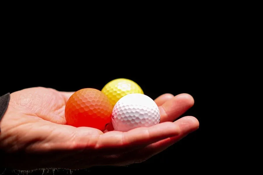 Un uomo con in mano tre palline da golf a quattro pezzi