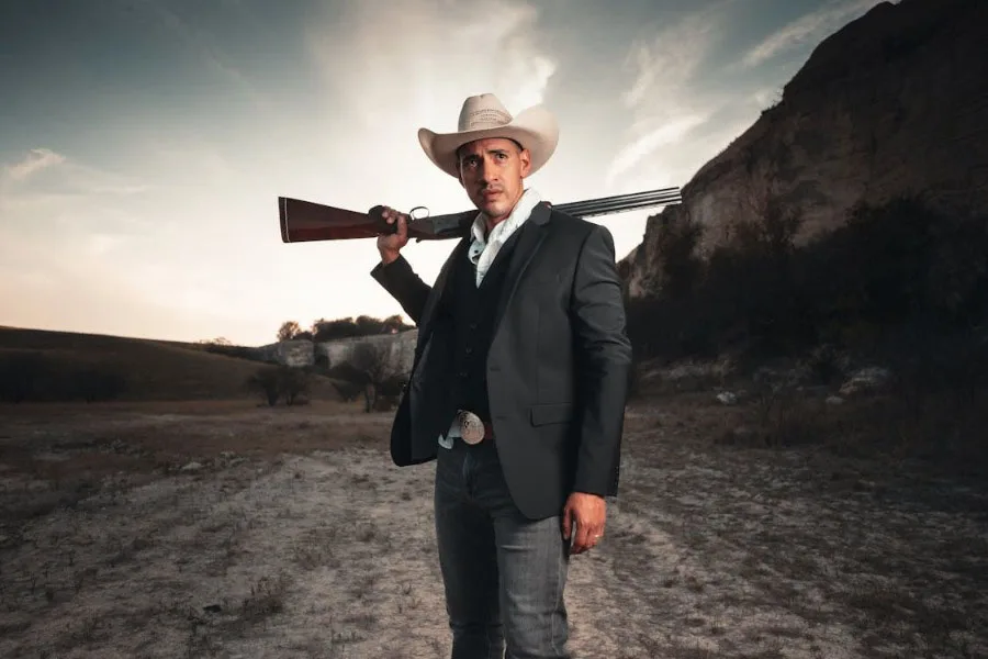 Um homem usando chapéu de cowboy e uma arma nos ombros