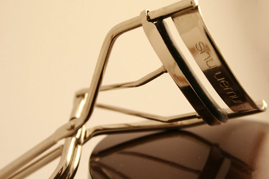 A metal eyelash curler on a colored background